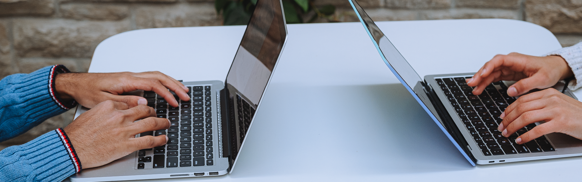 Close-up image of two laptops with student hands on the keyboards